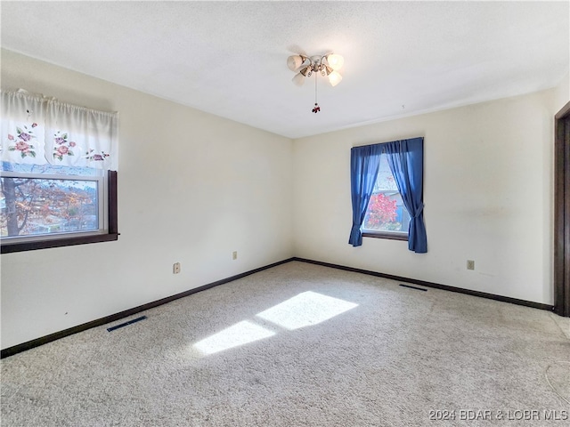 spare room featuring light carpet and a textured ceiling