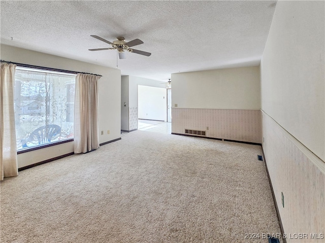 carpeted spare room with a textured ceiling and ceiling fan