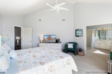 carpeted bedroom with connected bathroom, ceiling fan, and high vaulted ceiling