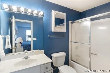 full bathroom featuring shower / bath combination with glass door, vanity, and toilet