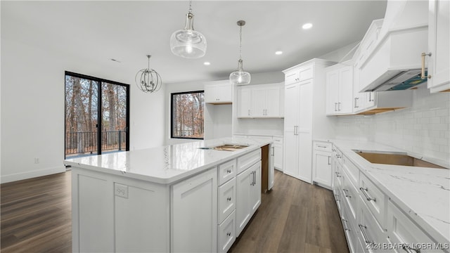 kitchen with white cabinets, a kitchen island, dark wood-type flooring, and pendant lighting