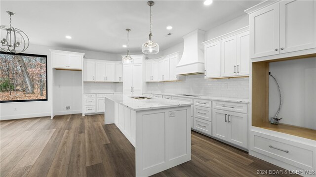 kitchen featuring a kitchen island, custom exhaust hood, decorative light fixtures, and white cabinets