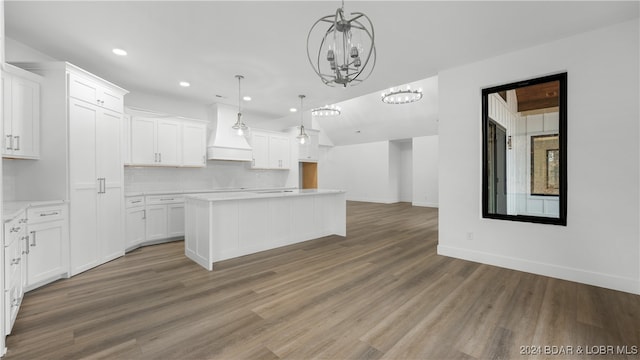 kitchen with decorative light fixtures, light countertops, white cabinets, a kitchen island, and premium range hood