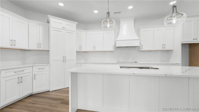 kitchen with light stone counters, decorative light fixtures, custom exhaust hood, visible vents, and white cabinets