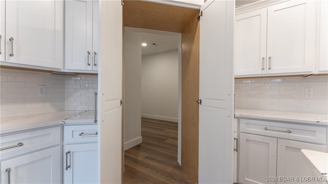 kitchen featuring light stone countertops, decorative backsplash, white cabinets, and dark wood finished floors