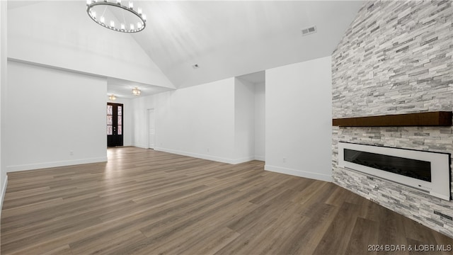 unfurnished living room featuring a fireplace, a notable chandelier, visible vents, wood finished floors, and high vaulted ceiling