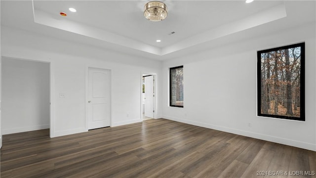 unfurnished bedroom with dark wood-type flooring, a raised ceiling, and baseboards