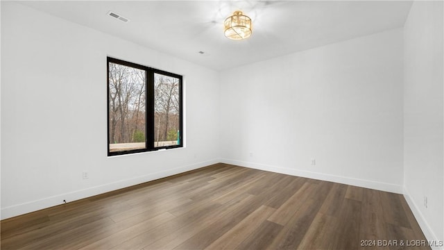 spare room with visible vents, baseboards, and wood finished floors