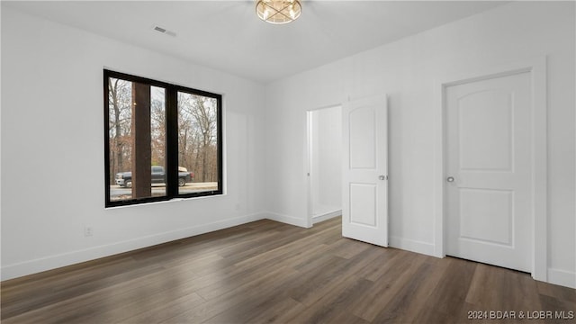 unfurnished bedroom featuring baseboards, visible vents, and dark wood-type flooring