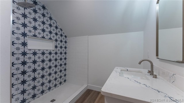 bathroom featuring vaulted ceiling, wood finished floors, vanity, and a tile shower