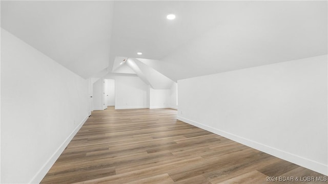 additional living space with lofted ceiling, recessed lighting, wood finished floors, and baseboards