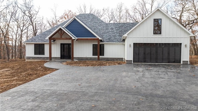 modern inspired farmhouse with a shingled roof, board and batten siding, and aphalt driveway