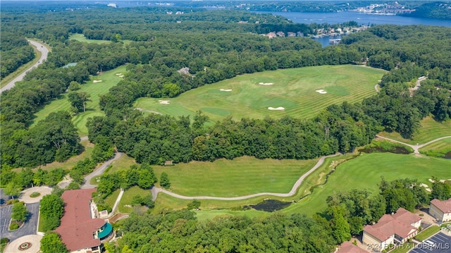 aerial view with golf course view, a water view, and a view of trees