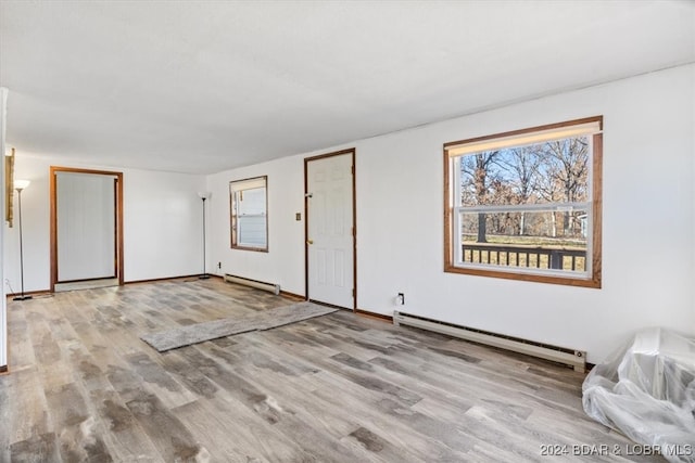 empty room featuring baseboard heating and light wood-type flooring