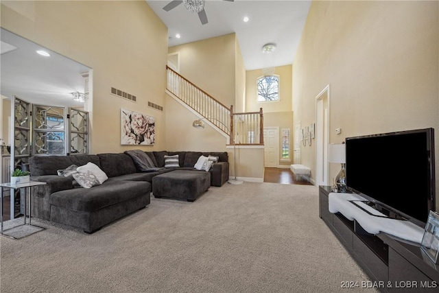 carpeted living room featuring a towering ceiling and ceiling fan