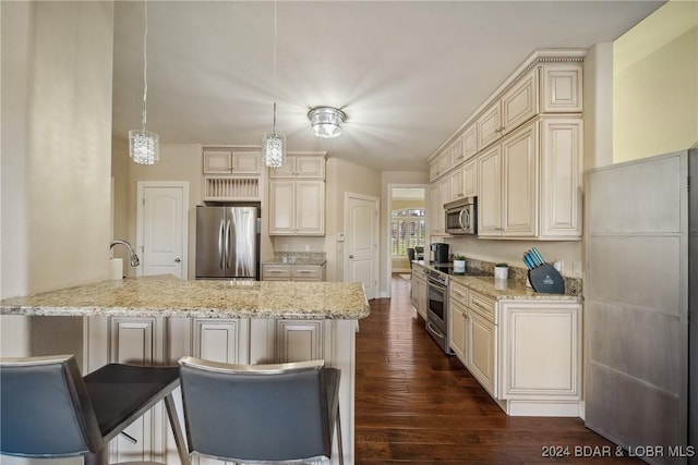 kitchen with appliances with stainless steel finishes, decorative light fixtures, dark hardwood / wood-style floors, and cream cabinets