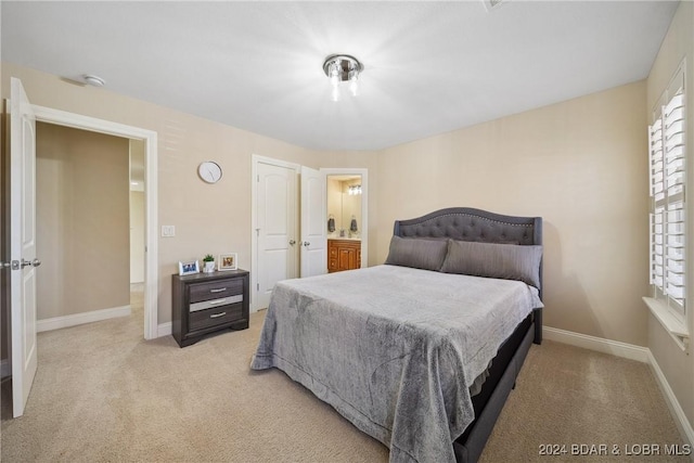 bedroom with light carpet and connected bathroom