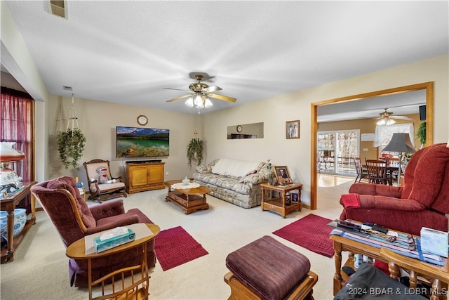 living room with ceiling fan, carpet, and a textured ceiling