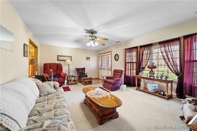 carpeted living room featuring ceiling fan and a textured ceiling