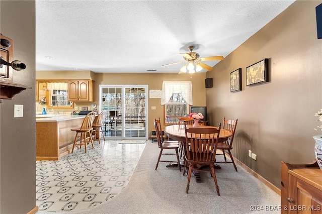 dining area with a textured ceiling, ceiling fan, and light carpet