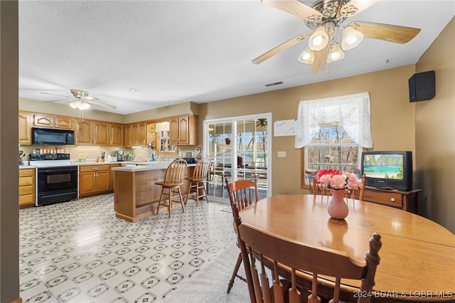 dining area featuring ceiling fan and a textured ceiling