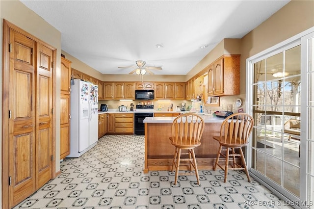 kitchen featuring a breakfast bar area, kitchen peninsula, ceiling fan, and white appliances