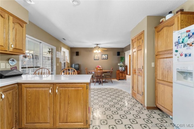 kitchen featuring white refrigerator with ice dispenser, kitchen peninsula, and ceiling fan