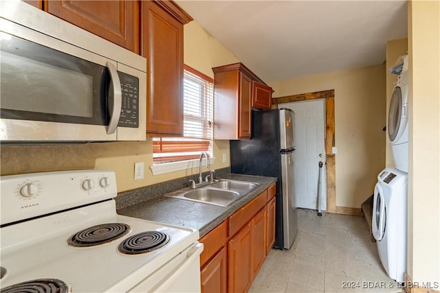 kitchen featuring stacked washer / dryer, sink, and appliances with stainless steel finishes