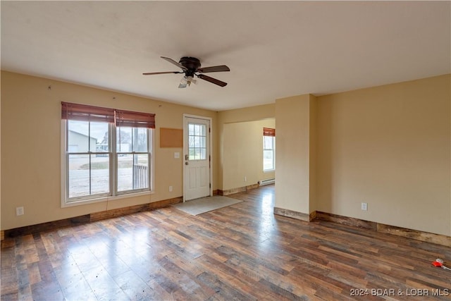 spare room with baseboard heating, ceiling fan, and dark wood-type flooring