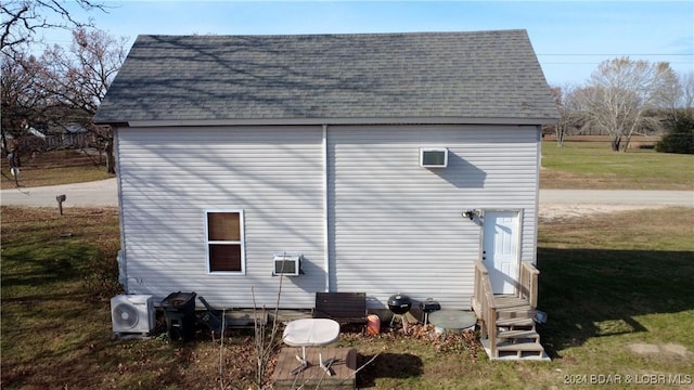 view of property exterior featuring a wall mounted air conditioner, ac unit, and a yard