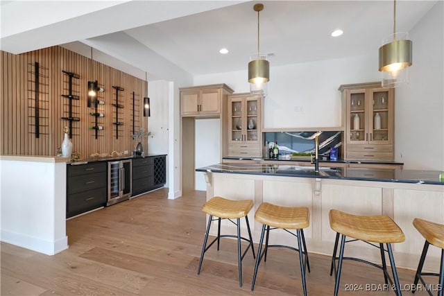 kitchen featuring kitchen peninsula, decorative light fixtures, wine cooler, and light hardwood / wood-style flooring