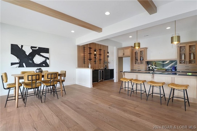 kitchen with beam ceiling, kitchen peninsula, light hardwood / wood-style floors, decorative light fixtures, and decorative backsplash