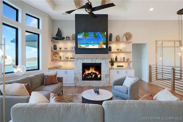 living room with ceiling fan, a large fireplace, and light hardwood / wood-style flooring