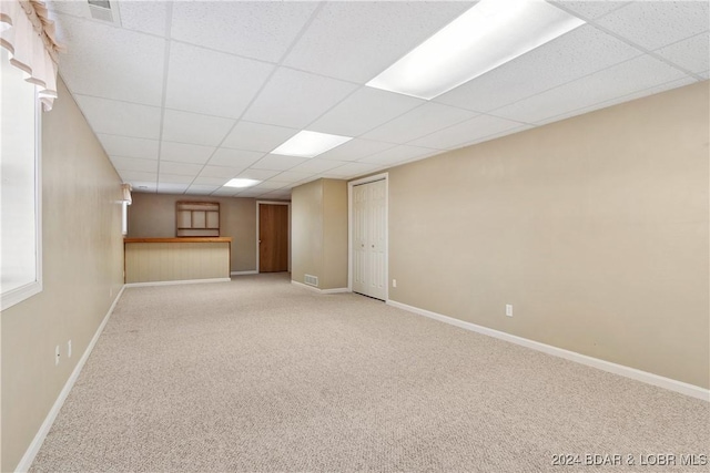 basement with a drop ceiling and light carpet