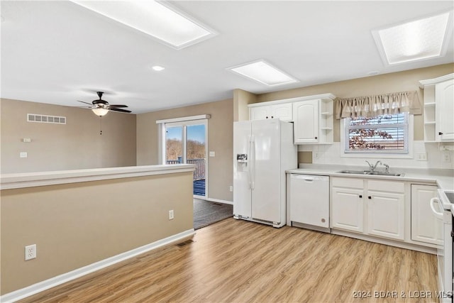 kitchen with tasteful backsplash, white cabinetry, sink, light wood-type flooring, and white appliances