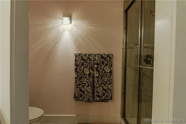 full bathroom featuring baseboards, a stall shower, and toilet
