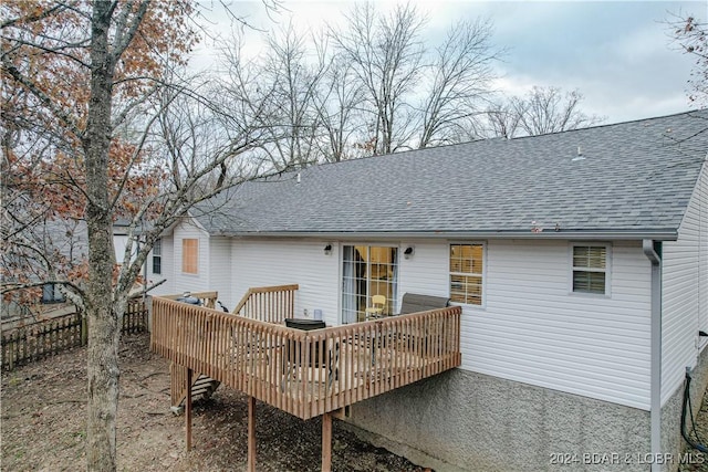 rear view of property featuring roof with shingles and a deck