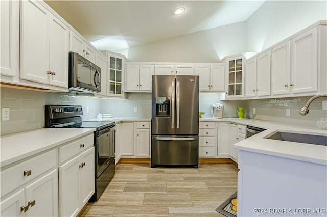 kitchen featuring white cabinetry, sink, lofted ceiling, decorative backsplash, and black appliances