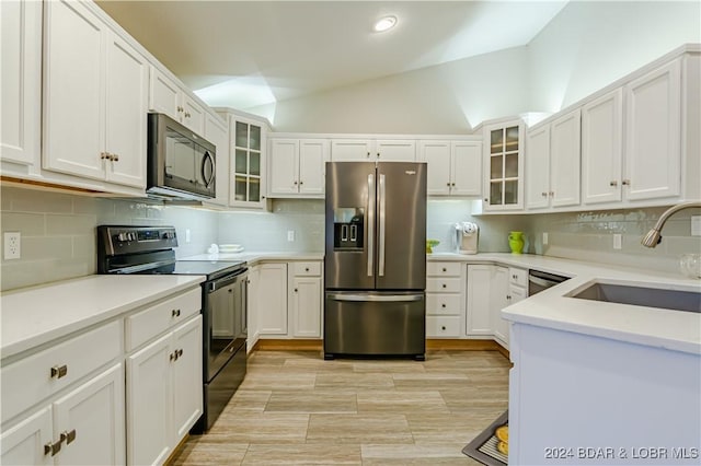 kitchen featuring lofted ceiling, a sink, black microwave, electric stove, and stainless steel fridge with ice dispenser