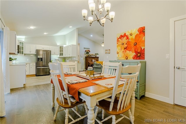 dining area featuring lofted ceiling, a chandelier, light wood-type flooring, and baseboards