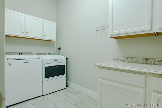 clothes washing area featuring cabinets and separate washer and dryer