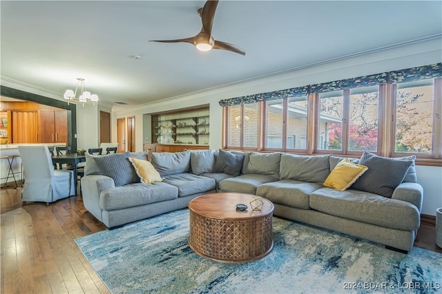 living area with ceiling fan with notable chandelier, ornamental molding, hardwood / wood-style flooring, and a healthy amount of sunlight