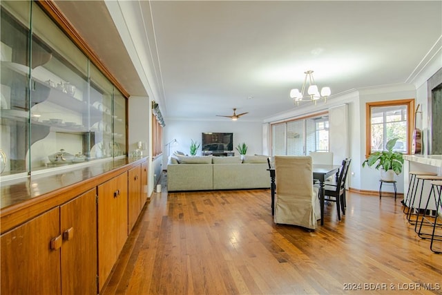 dining area with crown molding, ceiling fan with notable chandelier, and light hardwood / wood-style floors