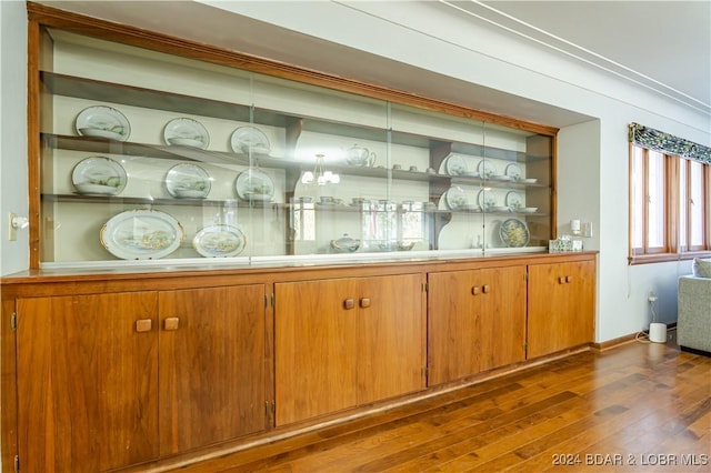 bar featuring dark wood-type flooring and built in shelves