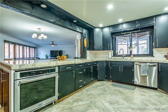 kitchen with appliances with stainless steel finishes, pendant lighting, ceiling fan with notable chandelier, sink, and crown molding