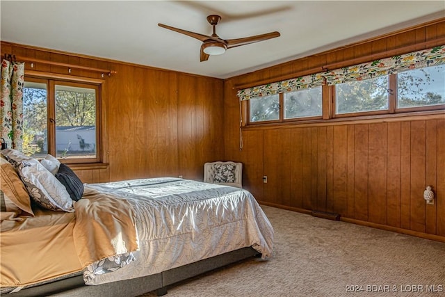 carpeted bedroom featuring ceiling fan and wooden walls