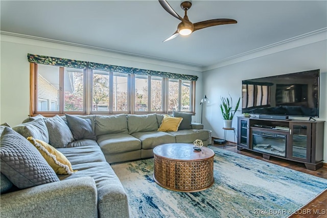 living area with ornamental molding, wood finished floors, a ceiling fan, and baseboards