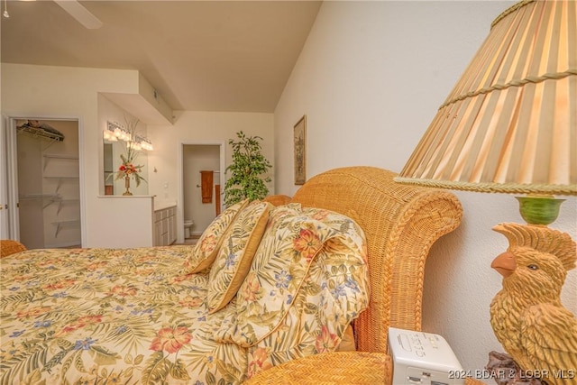 bedroom featuring a spacious closet, ceiling fan, ensuite bathroom, vaulted ceiling, and a closet