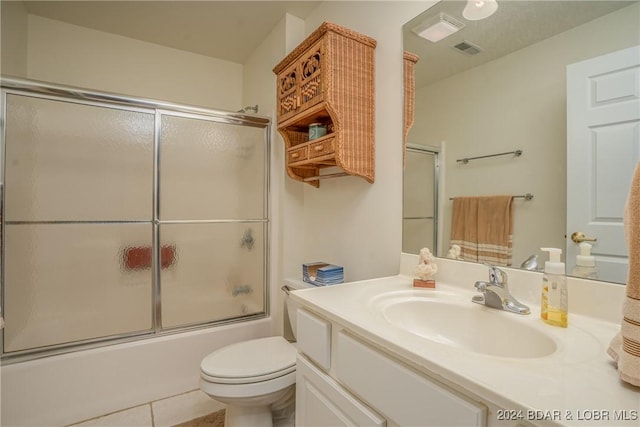 full bathroom featuring tile patterned floors, vanity, combined bath / shower with glass door, and toilet