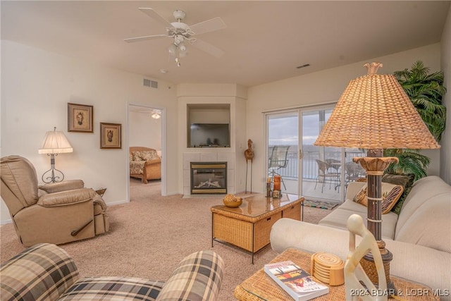 living room featuring a fireplace, light colored carpet, and ceiling fan